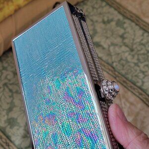 Holographic crocodile-embossed vinyl clutch bag with a silver-tone frame